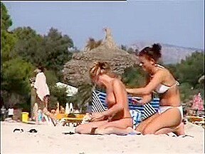 Deux copines topless simulent de baiser sur la plage